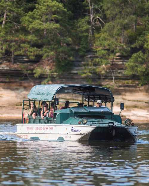 A tour boat with passengers cruising on calm water, surrounded by lush greenery and rocky cliffs.