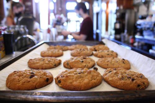 Freshly baked cookies on a tray, with a blurred barista in the background preparing drinks.