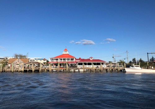 A waterfront scene featuring a red-roofed building and wooden docks under a clear blue sky.