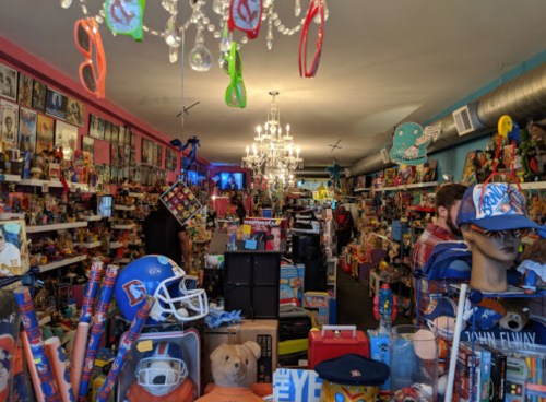 A colorful toy store filled with shelves of toys, collectibles, and decorations, featuring a chandelier and playful displays.