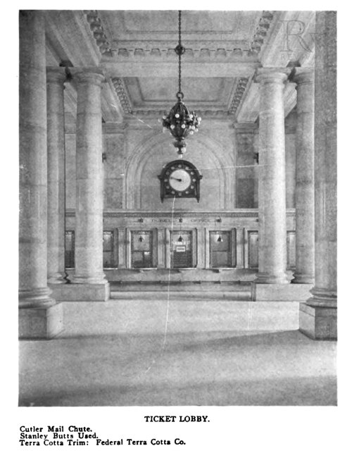 Historic ticket lobby featuring tall columns, a large clock, and a mail chute, with terra cotta trim details.