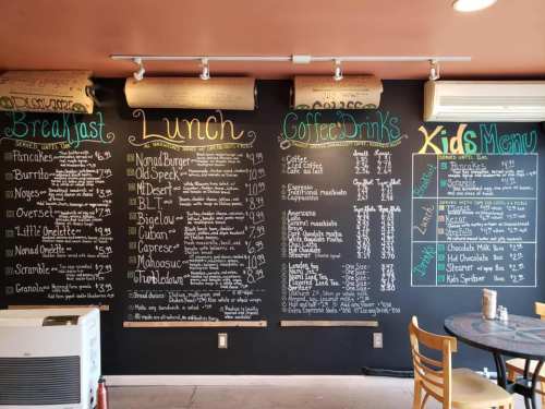 Chalkboard menu featuring breakfast, lunch, coffee drinks, and kids' menu items with prices listed.