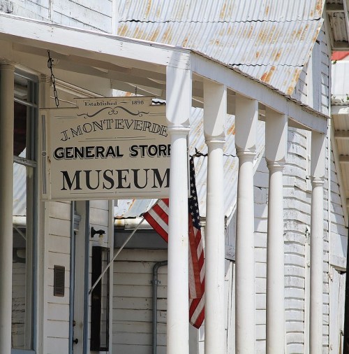 Sign for J. Monteverde General Store Museum, featuring a weathered building and an American flag.