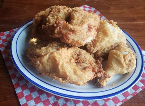 A plate of crispy fried chicken pieces on a checkered paper background.