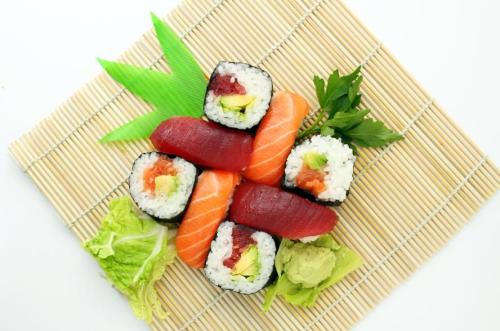 A colorful assortment of sushi rolls, including tuna and salmon, garnished with wasabi and lettuce on a bamboo mat.