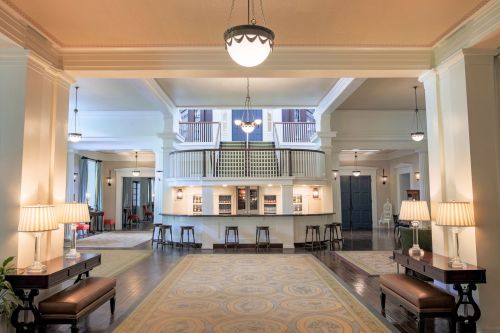Elegant hotel lobby with a spacious layout, featuring a reception area, seating, and decorative lighting.
