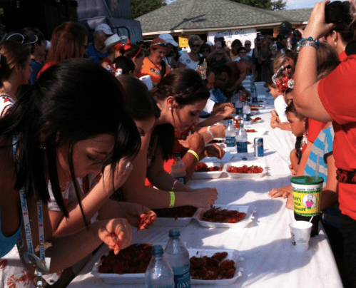 A crowd watches as participants compete in a crawfish eating contest at an outdoor event.