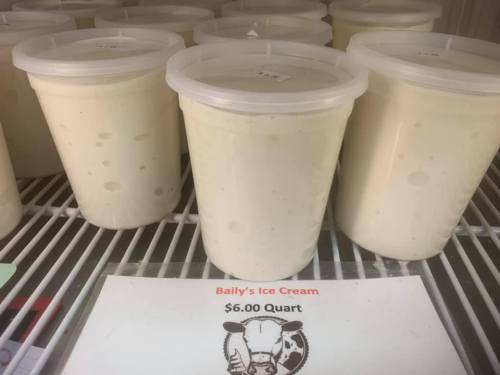 Containers of ice cream in a freezer, with a sign displaying the price of $6.00 per quart.