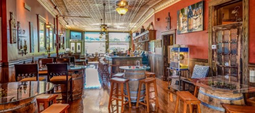 A cozy restaurant interior featuring wooden tables, a bar, and warm lighting, with a vintage decor style.
