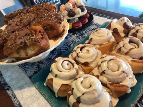 A display of sweet pastries, including cinnamon rolls with icing and sticky buns topped with nuts and caramel.
