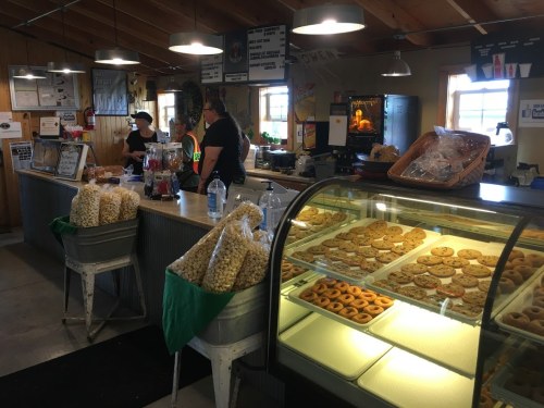 A cozy bakery with a display case of cookies and pastries, and staff serving customers at the counter.