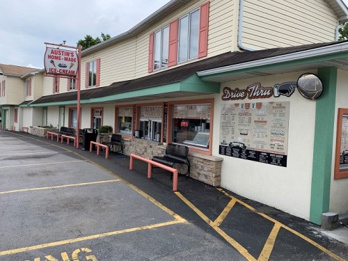 Exterior of Austin's Homemade Ice Cream shop featuring a drive-thru menu and benches outside. Sign reads "Open."