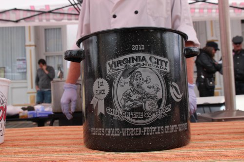 A black pot with "Virginia City, Nevada" and "1st Place Chili on the Comstock" engraved on it, displayed at an event.
