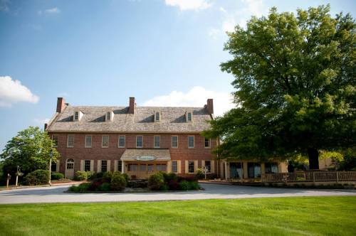 A large brick building with a welcoming entrance, surrounded by green grass and trees under a blue sky.