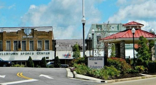 Welcome sign to Tylertown with a sports center and landscaped area under a blue sky.