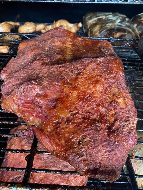 A close-up of a perfectly smoked brisket on a grill, with a rich, dark crust and juicy texture.