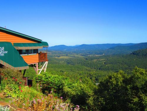 A scenic view from a mountain lodge overlooking lush green valleys and distant blue hills under a clear blue sky.