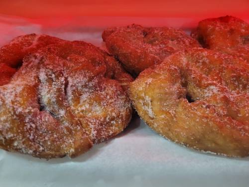 Three sugar-coated pastries on parchment paper, illuminated with a warm red light.