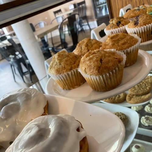 A display of freshly baked muffins and iced pastries in a cozy café setting.