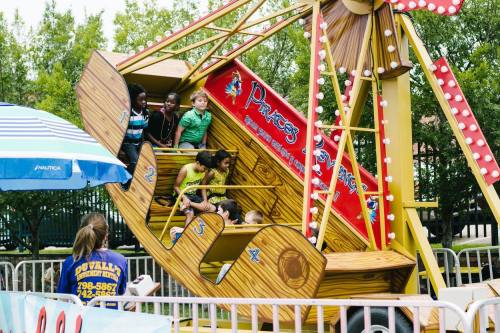 Children enjoying a colorful amusement ride at a fair, with excited expressions and a vibrant background.