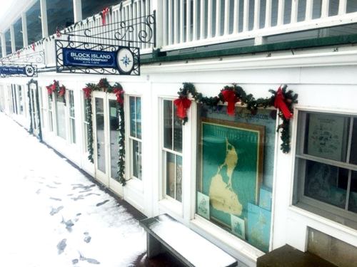 Snow-covered storefront decorated with holiday garlands and a sign for Block Island Trading Company.