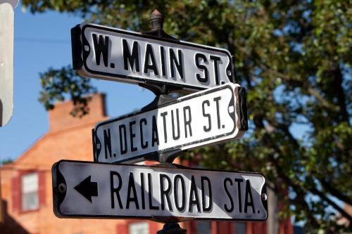 Street sign with directions for W. Main St., N. Decatur St., and Railroad St. against a clear blue sky.