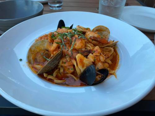 A plate of seafood pasta with shrimp, mussels, and clams in a rich tomato sauce, garnished with herbs.