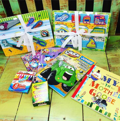 A colorful assortment of children's activity books, crayons, and puzzles, neatly arranged with ribbons on a wooden surface.