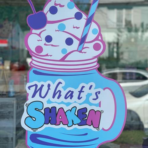 Colorful sign featuring a milkshake in a jar with the text "What's Shaken" in bold, playful letters.
