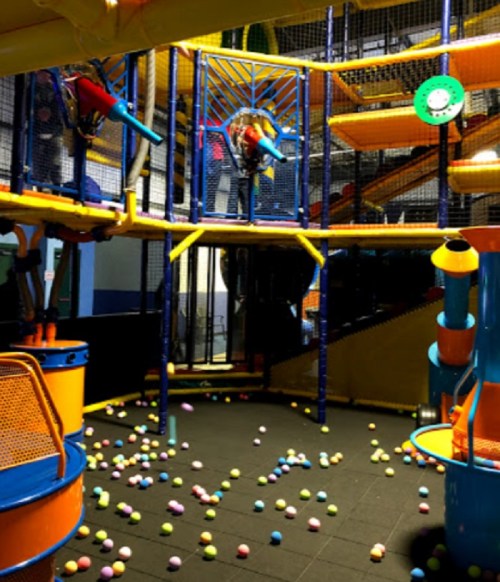 Colorful indoor play area with climbing structures and scattered balls on the floor.