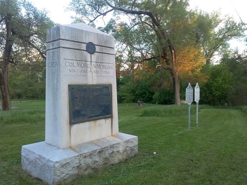 A stone monument dedicated to Col. Morgan Morgan, surrounded by greenery and trees.