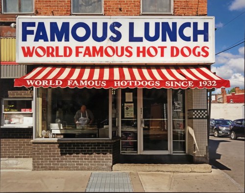 A storefront with a red and white striped awning, featuring "Famous Lunch" and "World Famous Hot Dogs" signage.