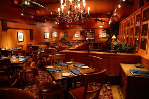 Cozy restaurant interior with wooden tables, chairs, and warm lighting, featuring a chandelier and decorative plants.