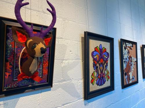 Colorful wall art featuring framed designs and a plush deer head with purple antlers.
