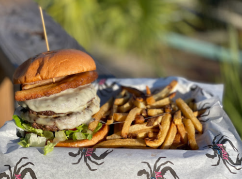 A juicy burger with melted cheese, lettuce, and a crispy bun, served with a side of golden fries on a paper-lined tray.