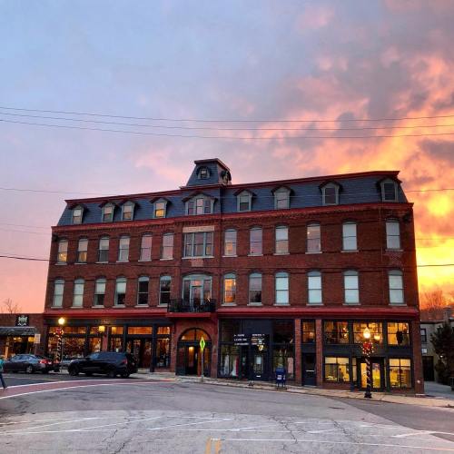 Historic brick building at sunset, with colorful sky and street activity in the foreground.
