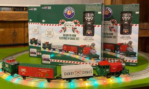 A colorful electric train set with festive packaging, featuring a green cargo car and a red engine, displayed on a circular track.