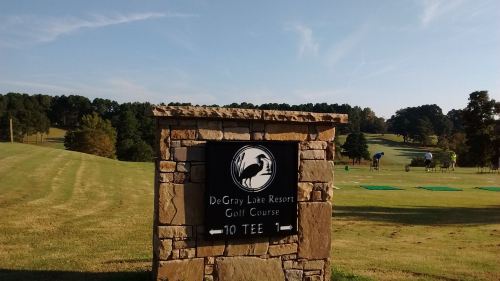 Sign for DeGray Lake Resort Golf Course with a heron logo, indicating the 10th tee, surrounded by green landscape.