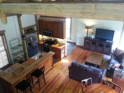A cozy, open-concept living space with wooden beams, a kitchen, and a comfortable seating area.