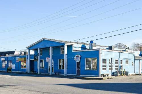 A bright blue building with multiple windows and a sign, located on a street with power lines overhead.