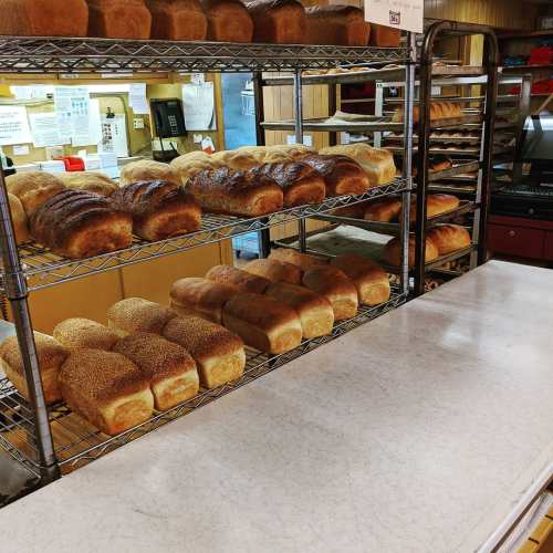 Freshly baked loaves of bread on wire racks in a bakery, with a clean countertop in the foreground.