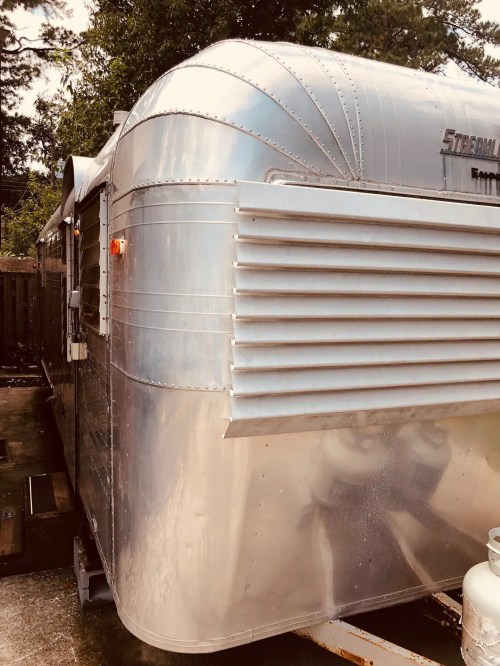 A vintage silver Airstream trailer parked outdoors, showcasing its iconic streamlined design and shiny exterior.