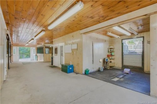 Interior of a spacious, well-lit room with wooden ceilings, featuring storage areas and a rubber mat on the floor.