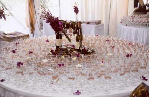 A beautifully arranged table with numerous glasses, wine bottles, and floral decorations for a celebration.