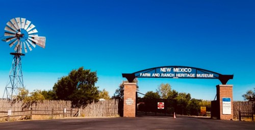 Entrance to the New Mexico Farm and Ranch Heritage Museum, featuring a windmill and clear blue sky.