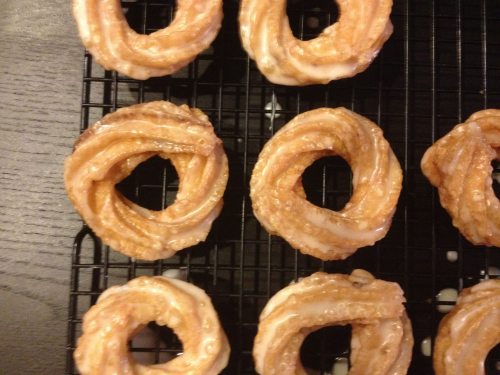 A close-up of glazed cinnamon rolls arranged on a cooling rack, showcasing their swirled, sticky texture.