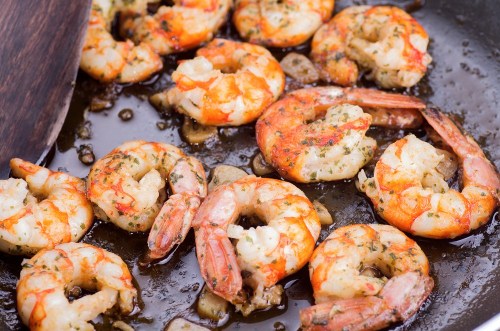 Sautéed shrimp in a skillet, seasoned and golden brown, with garlic and herbs.