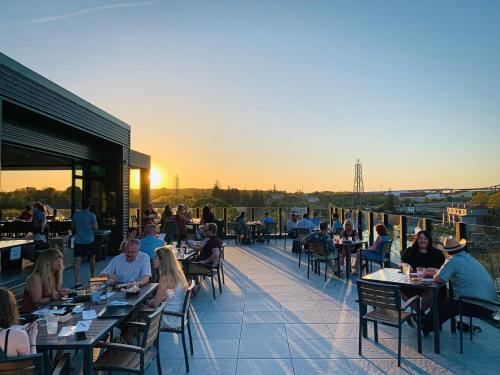 A rooftop dining area at sunset, with people enjoying meals and drinks against a scenic backdrop.
