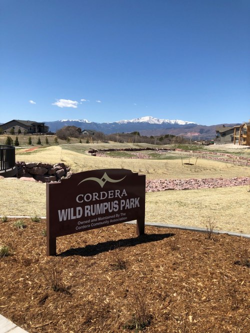 Sign for Cordera Wild Rumpus Park with mountains in the background and a clear blue sky.