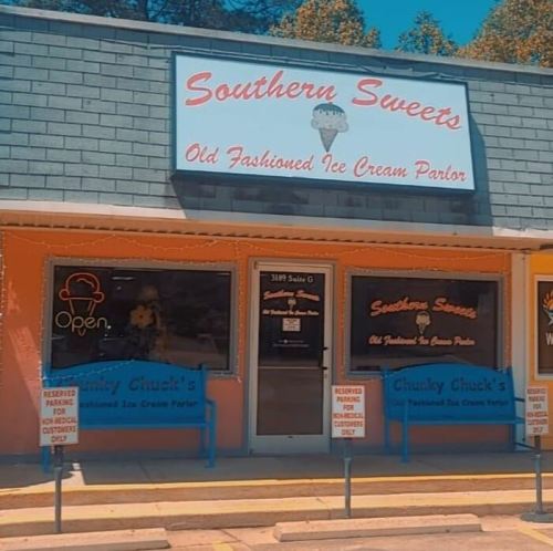 Exterior of Southern Sweets ice cream parlor, featuring a colorful sign and open door, with reserved seating outside.